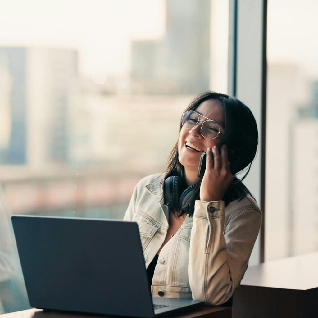 smiling woman on phone with laptop in office