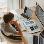 high angle shot of a boy sitting on grey chair while using his laptop computers