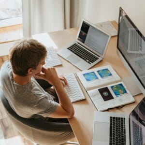 high angle shot of a boy sitting on grey chair while using his laptop computers