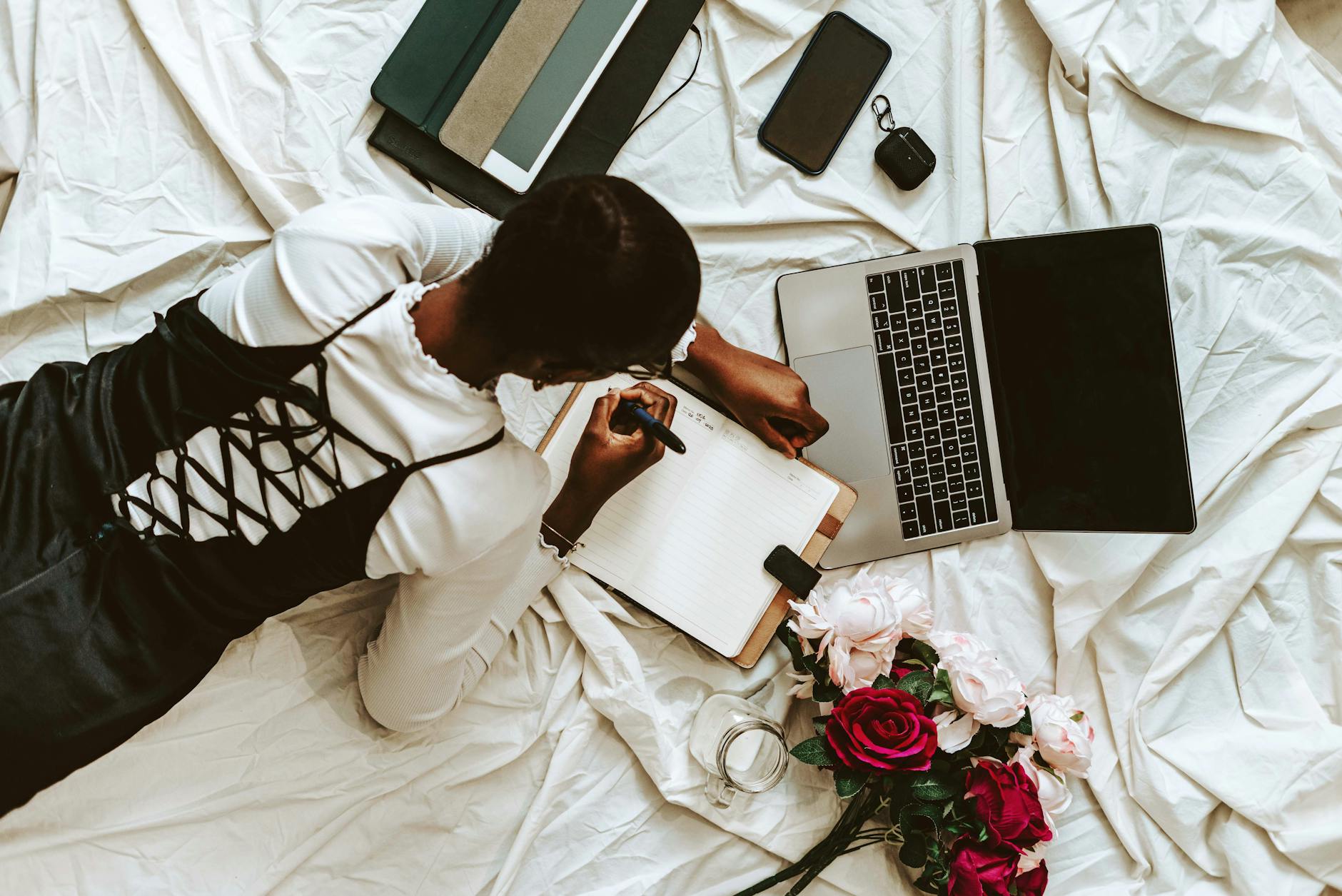 a woman laying on a bed with a laptop and flowers
