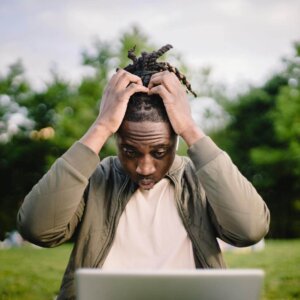 stressed black male entrepreneur working on laptop in park